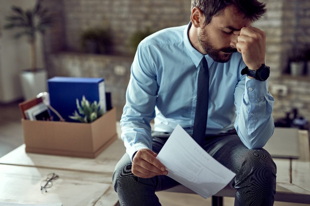 jovem empresario frustrado segurando cabeca com dor depois de ser demitido no trabalho
